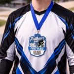 A BMX racer wearing a first-place Father’s Day medallion over a blue, black, and white racing jersey.
